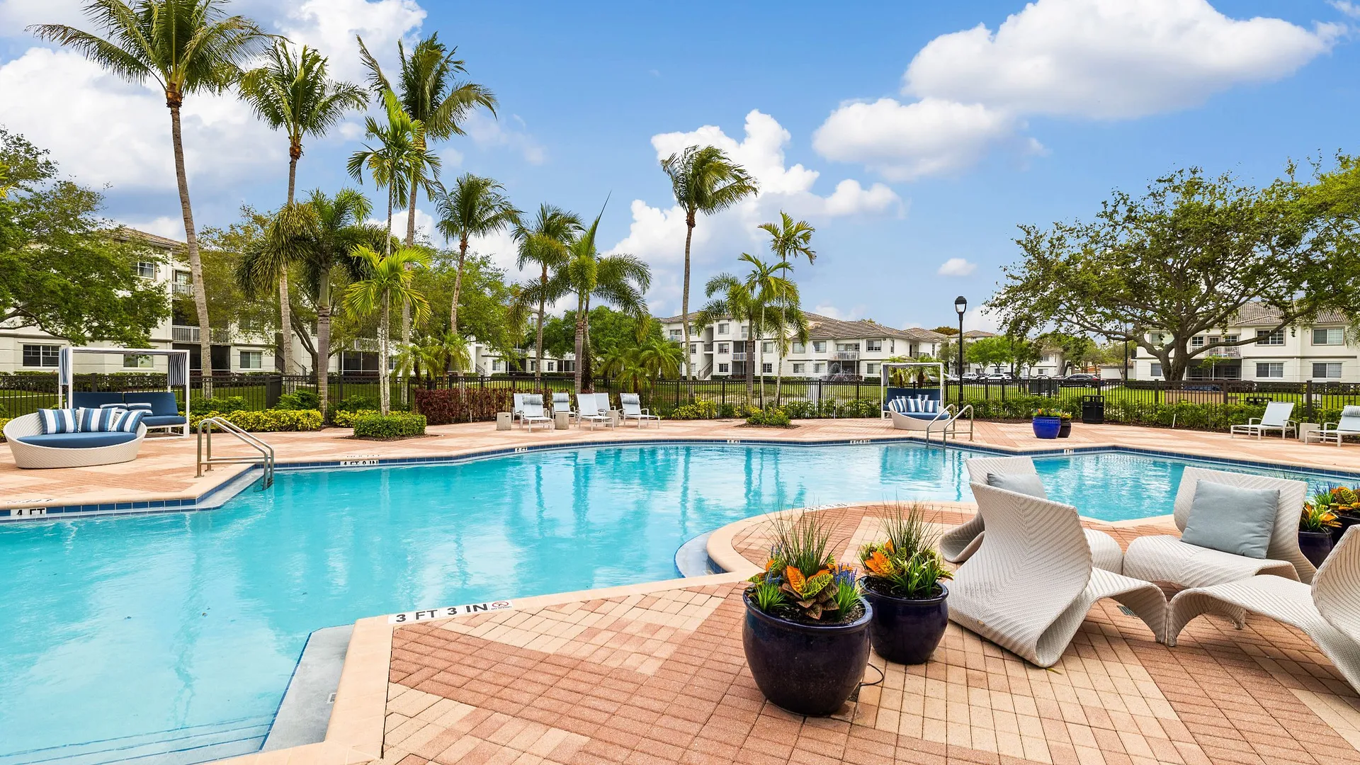 A serene pool area surrounded by palm trees and comfortable lounge seating.