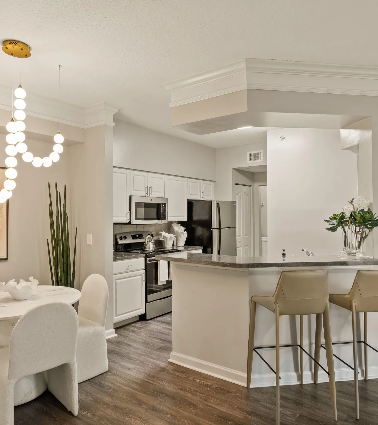 Modern kitchen and dining area with stylish decor and illuminated chandelier.