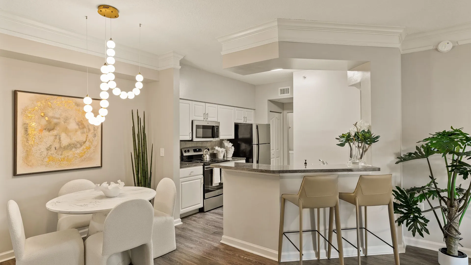 Modern kitchen and dining area with stylish decor and illuminated chandelier.