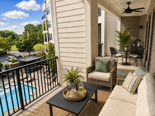 A balcony with a table and chairs overlooking a pool.