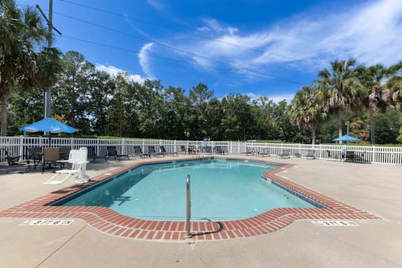 a pool with a fence and chairs around it