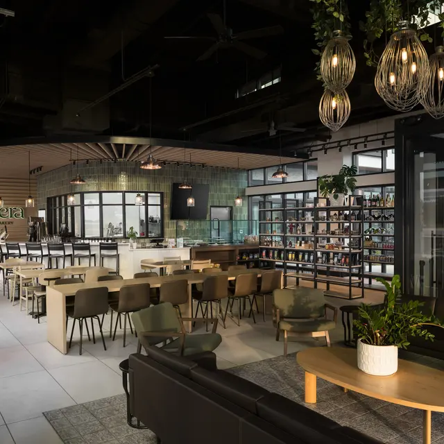 A stylish restaurant interior featuring wooden tables, modern furniture, and a bar area with shelves of drinks.
