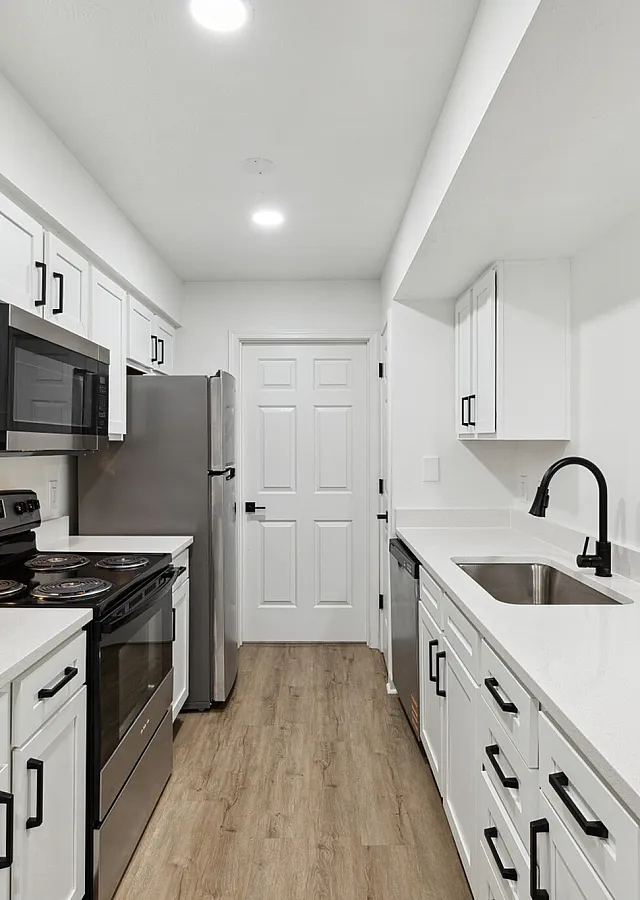 Sleek modern kitchen with elegant white cabinetry, stainless steel appliances, and beautiful wood flooring.