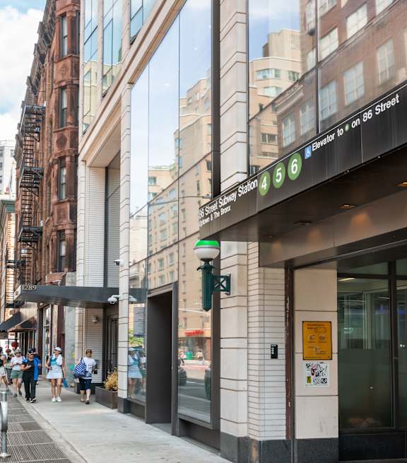 A street view with people walking on the sidewalk and a building with a sign that says "5th Ave Station".