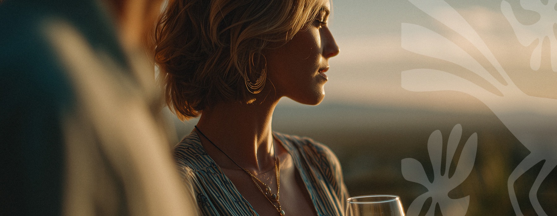 Woman at sunset looking off into the distance with a glass of wine