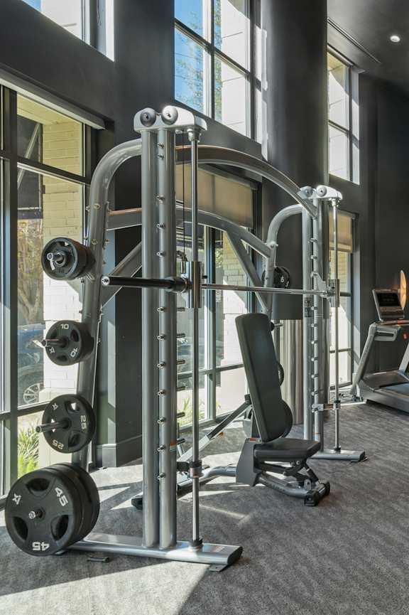 a gym with weights and cardio equipment in a building with large windows