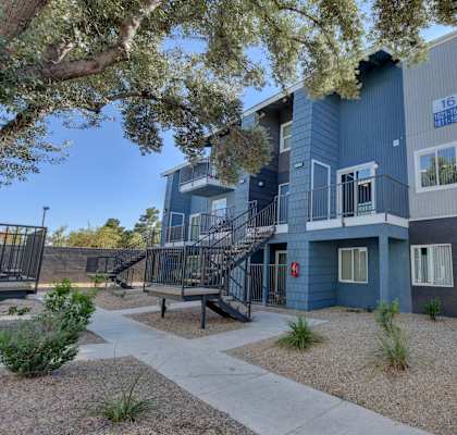 a blue apartment building with stairs and a sidewalk