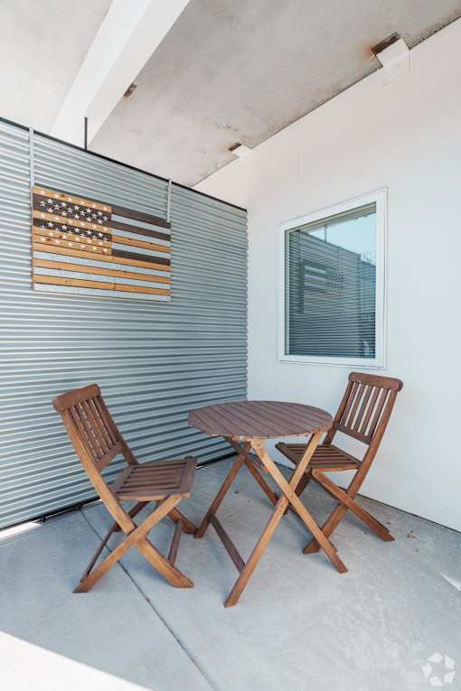 Two wooden chairs and a table are on a patio.