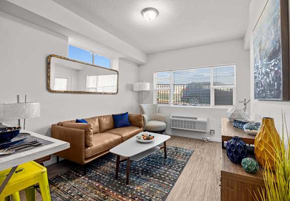 A living room with a brown couch and a yellow stool.