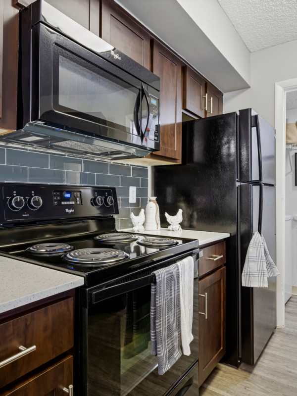 Apartment kitchen with black colored appliances including refrigerator at Centro at Davie Apartments, Davie, Florida 