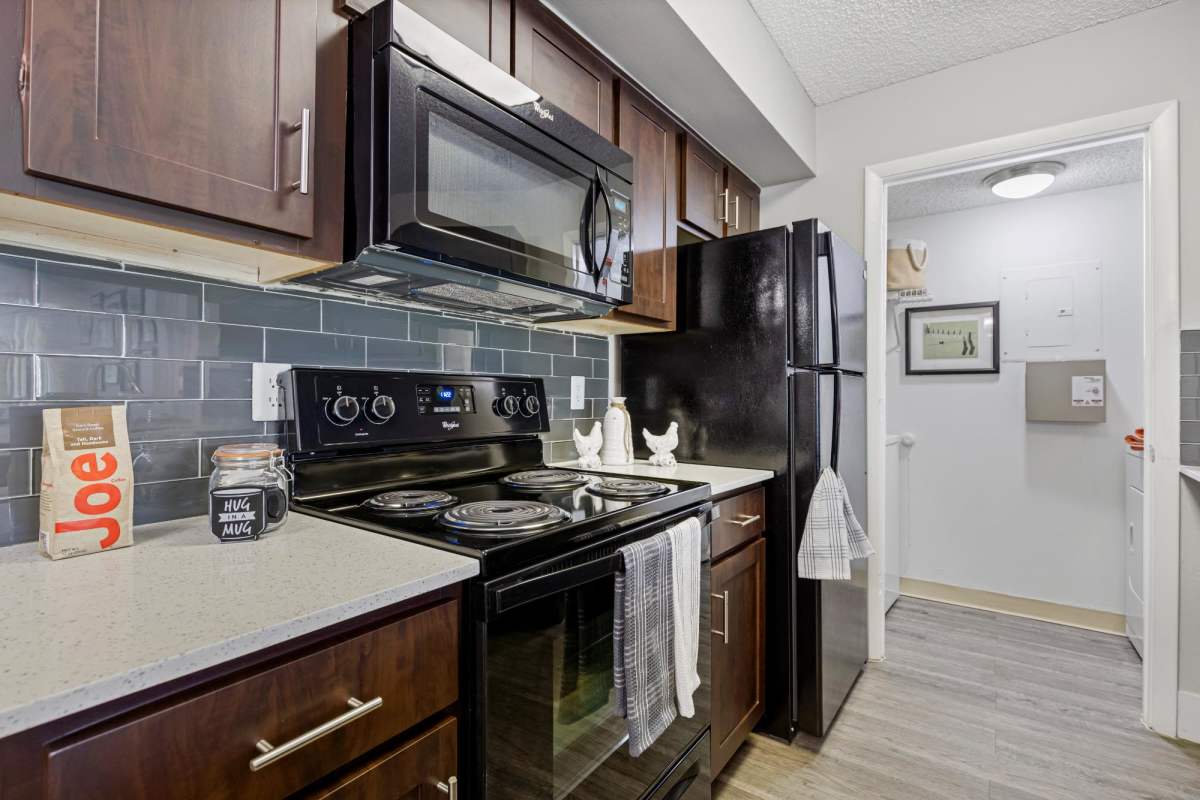 Model kitchen with black appliances at Centro at Davie Apartments, Davie, Florida