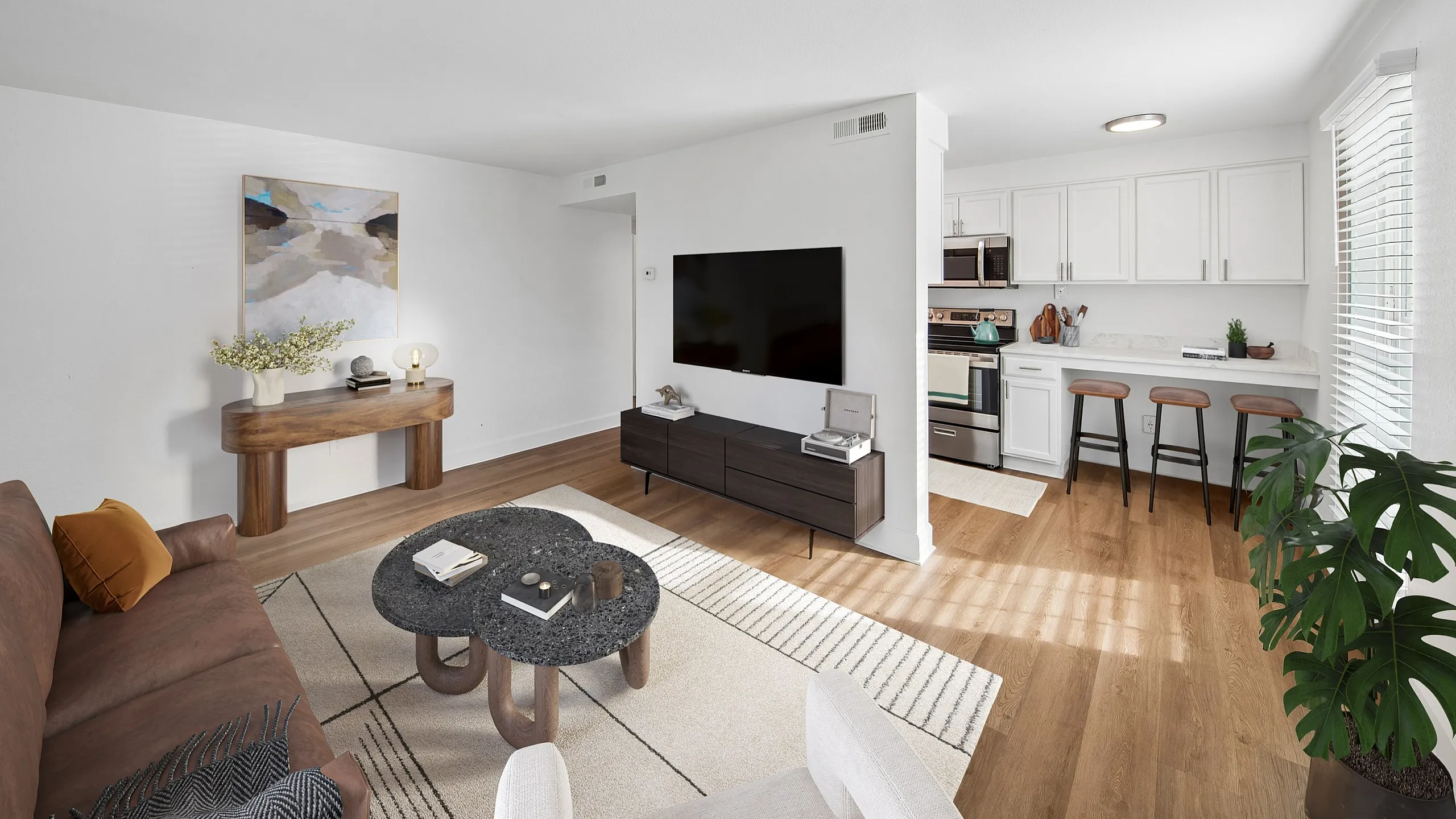 Modern open-concept living room and kitchen with sleek appliances, stylish decor, and abundant natural light.