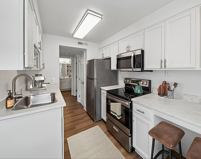 Modern kitchen with sleek stainless steel appliances, elegant white cabinetry, and a stylish marble countertop, perfect for culinary enthusiasts.