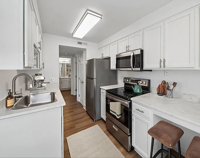 Modern kitchen with sleek stainless steel appliances, elegant white cabinetry, and a stylish marble countertop, perfect for culinary enthusiasts.