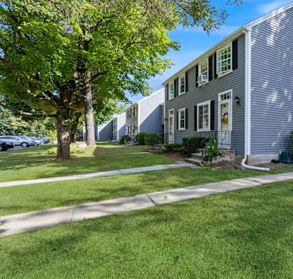 A grey house with a green lawn in front.