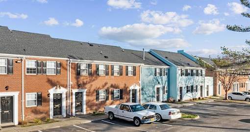 A row of houses with cars parked in front.