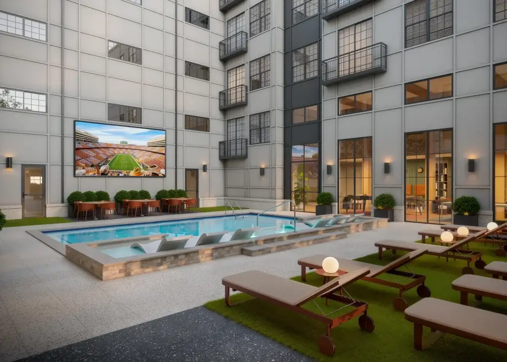 side view of the resort-style pool courtyard at Signature on Grand featuring a luxury swimming pool and a massive outdoor Jumbotron for student movie nights.