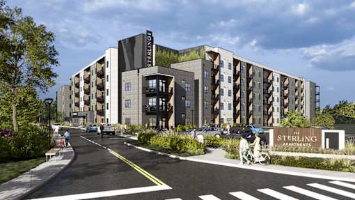 A Sterling apartment complex is shown with a person riding a bicycle on the street in front.
