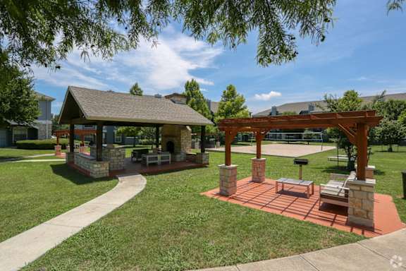 A gazebo is surrounded by a brick patio and a stone wall.