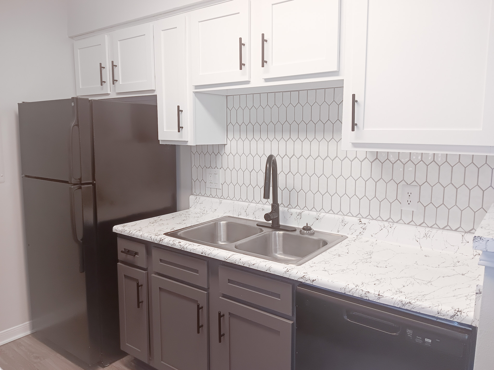 White tile backsplashes and black appliances inside apartment kitchens at The Woodlands