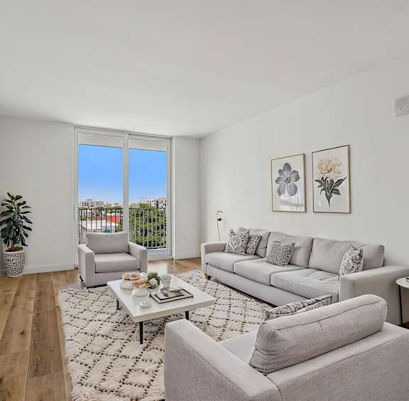 A living room with a grey couch, a coffee table, and a flat screen TV.