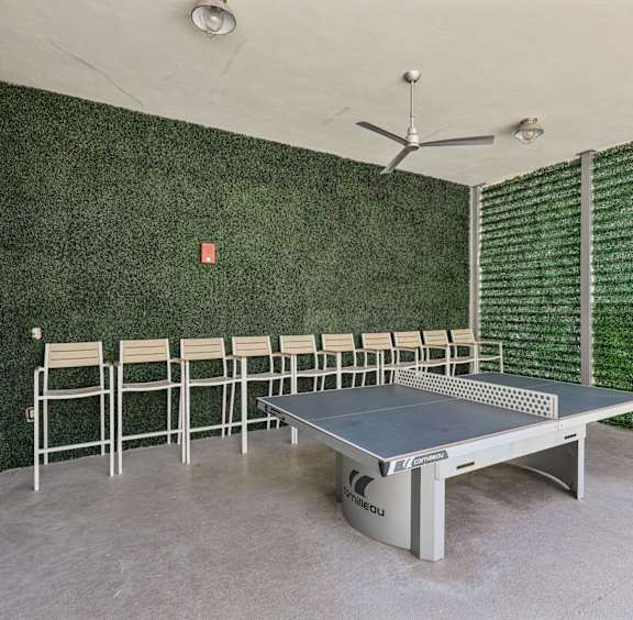 A ping pong table is in the middle of a room with a green wall.