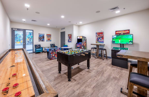 A room with a pool table, arcade games, and a TV. at Trinity Woods Apartments, Independence, 64015