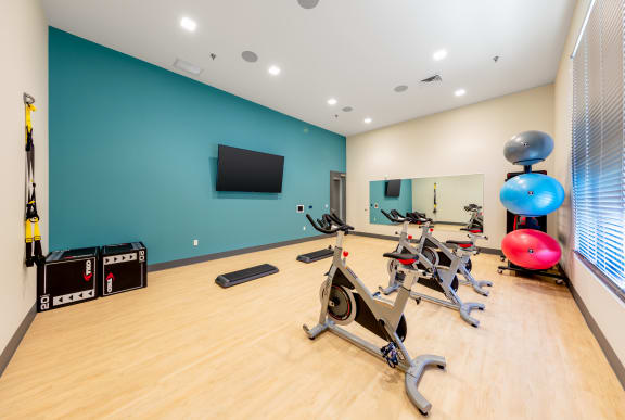 A gym with exercise equipment and a television on the wall. at Trinity Woods Apartments, Independence, 64015