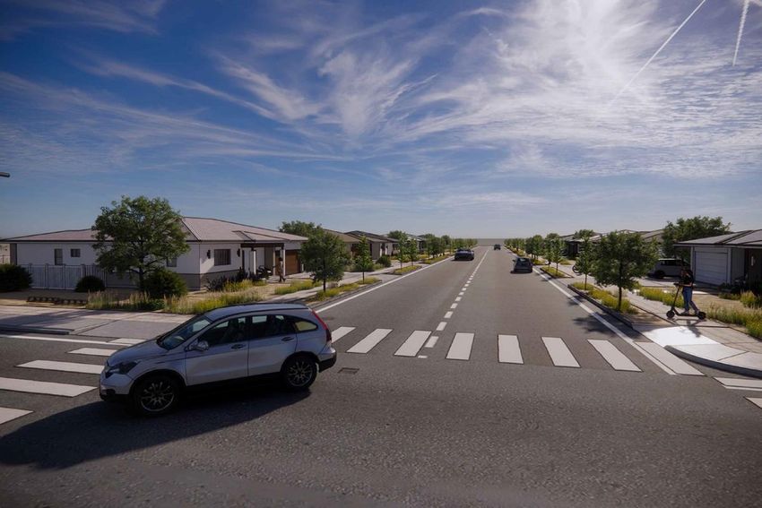 car driving down a community road with houses on both sides and a blue sky