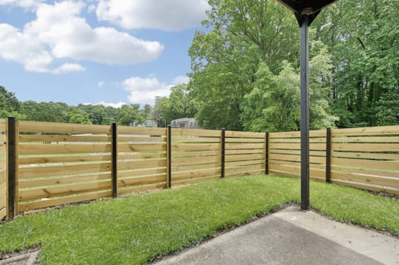 a wooden fence in a backyard with grass and trees at Rosen at North Hills, Raleigh, NC