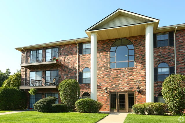Brick apartment building with balconies and arched windows.