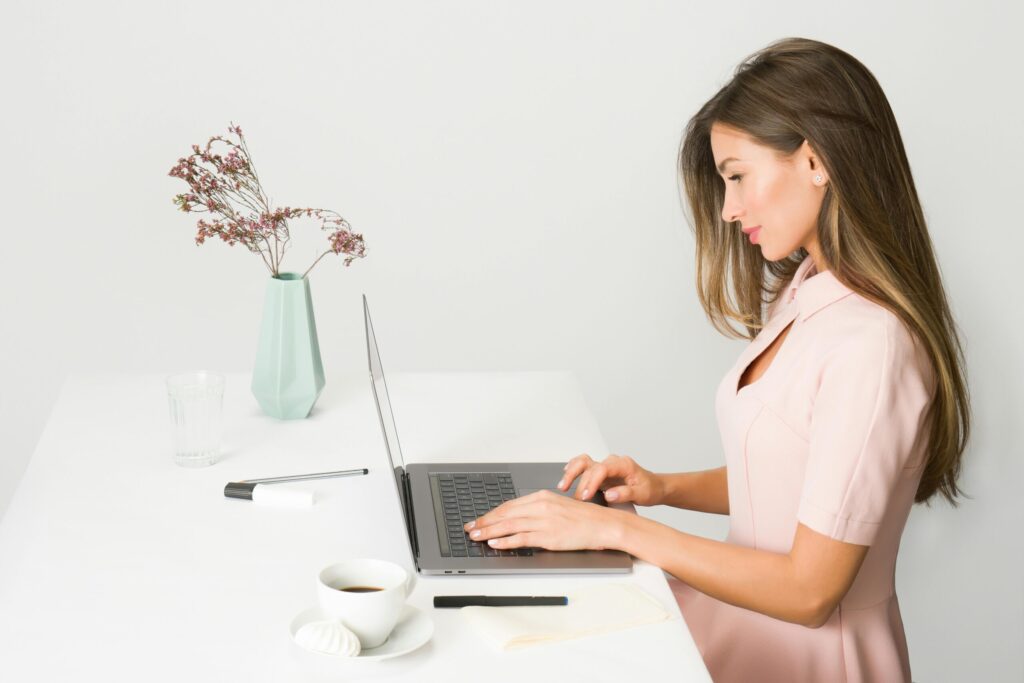 woman working in a pink dress on her laptop at new business centers at new apartments in Houston, TX at Allora Med Center!
