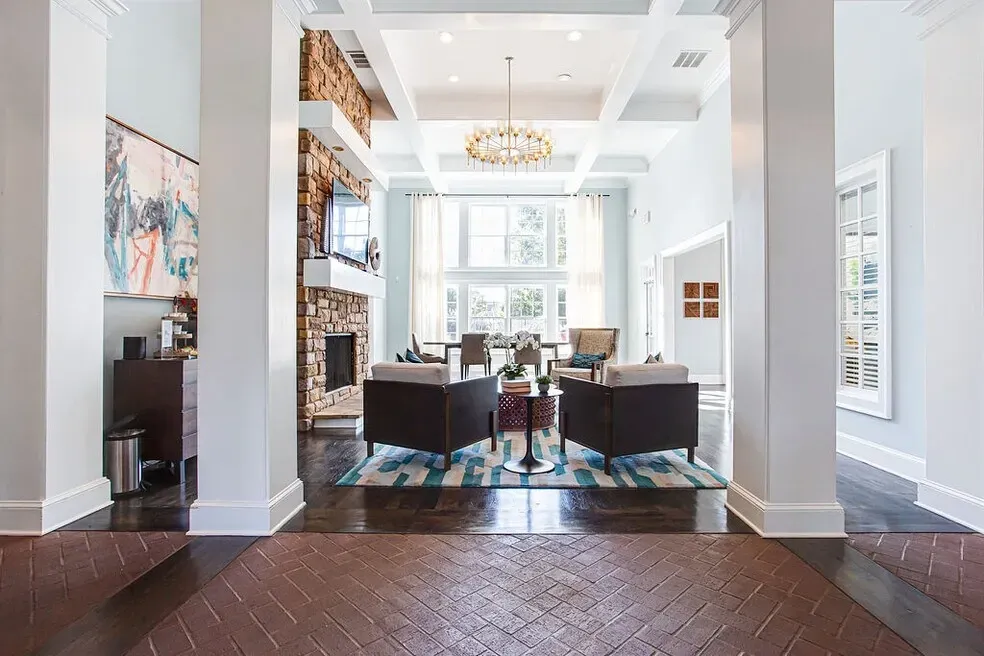 Bright modern lobby lounge with high ceilings, dark sofas, chandelier, and large windows Preserve at Mill Creek in Buford, GA