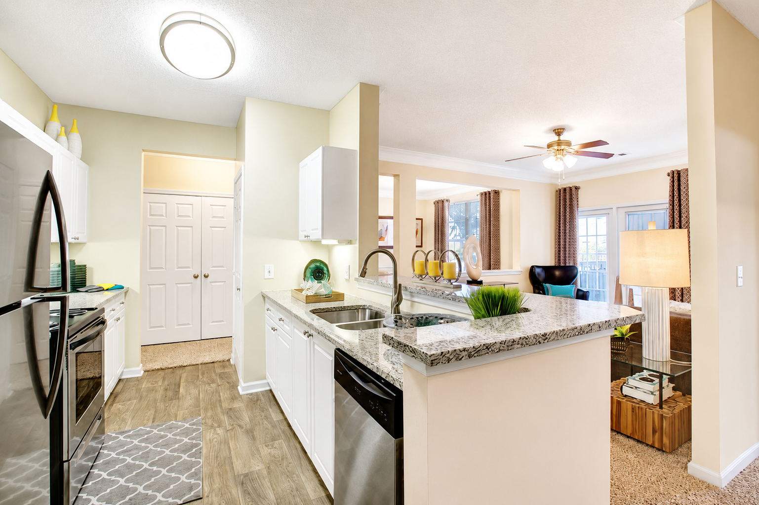 Bright modern kitchen with white cabinets, granite island, and view into a sunlit living room Preserve at Mill Creek