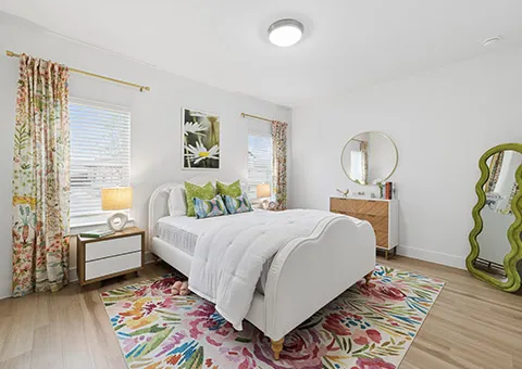 Bright and inviting bedroom with elegant decor, featuring a cozy bed, vibrant floral accents, and ample natural light.