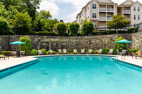 A swimming pool surrounded by a stone wall and chairs with umbrellas at Chesapeake Ridge, North East, Maryland