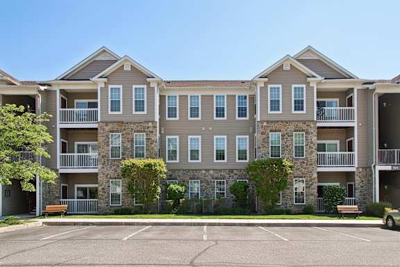 A large apartment complex with a parking lot in front.