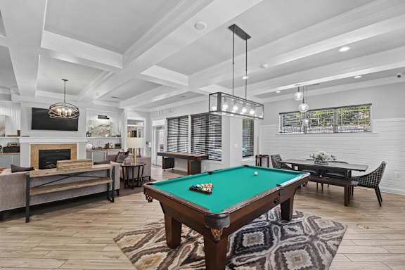 A pool table with green felt in a room with a fireplace and a TV.