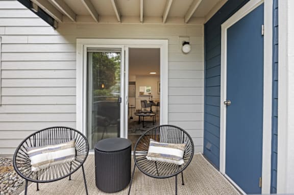 Two black chairs with white cushions are on a porch at 2000 Lake Washington Apartments in Renton, Washington 98056