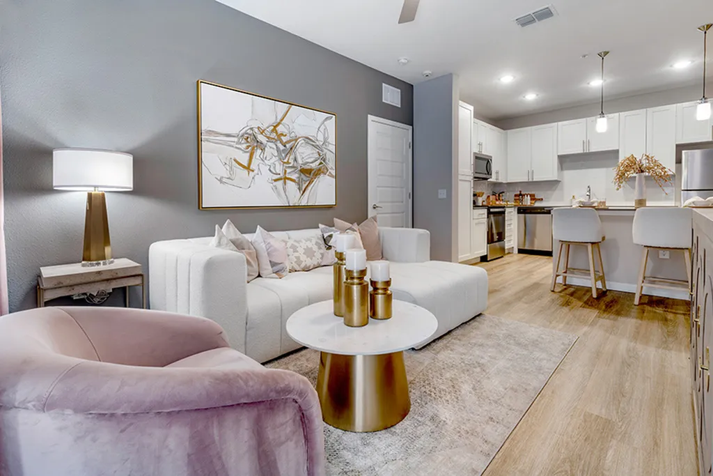 Living room with sofa, hardwood style floors and kitchen with white cabinets and stainless steel apploiances