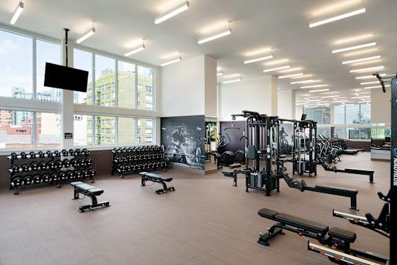 A gym with a variety of equipment including weights and machines. at Olympic + Hill Apartments, Apartments, Los Angeles, CA