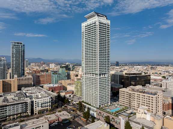 A cityscape with a tall building in the foreground. at Olympic + Hill Apartments, Apartments, Los Angeles, CA