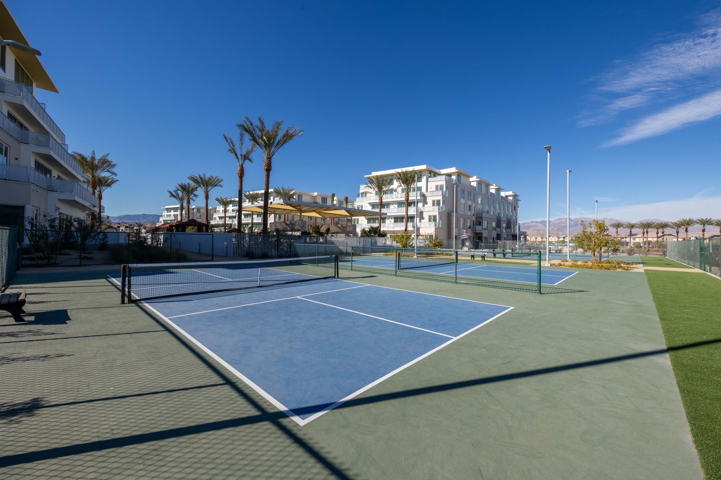 Evora A scenic view of a tennis court located at a resort in Las Palmas, surrounded by lush greenery and clear blue skies.