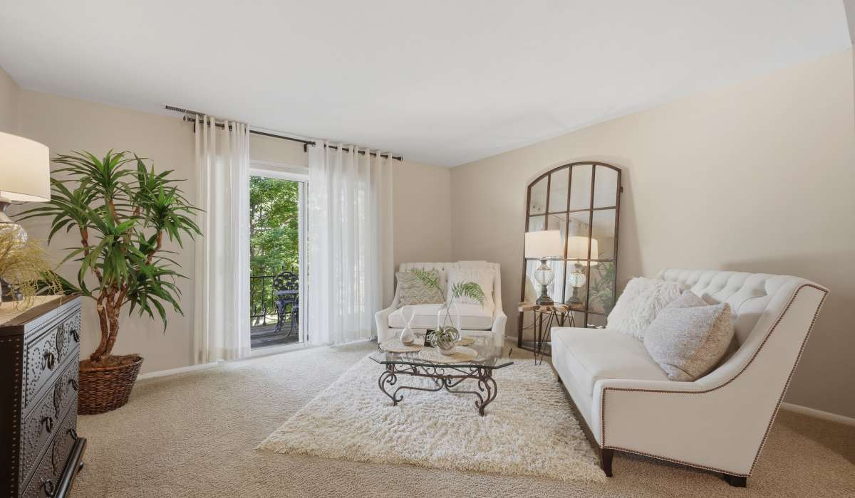 Living room with carpet flooring and access to patio at Beau Jardin Apartments in St. Louis, Missouri