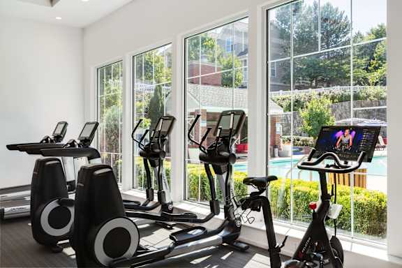 a gym with exercise equipment and windows overlooking a pool at Residences at Stevens Pond, Saugus, MA