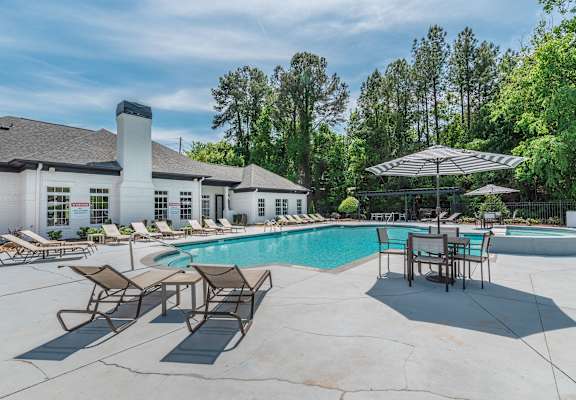 A pool area with lounge chairs and a table.