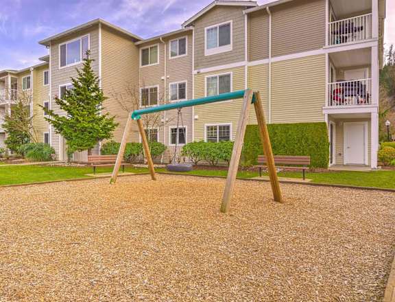 A playground with a slide in front of apartment buildings. at Valley Springs Apartments, Washington