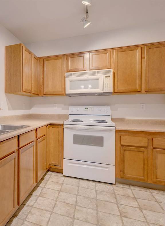 A kitchen with white appliances and wooden cabinets. at Valley Springs Apartments, Washington