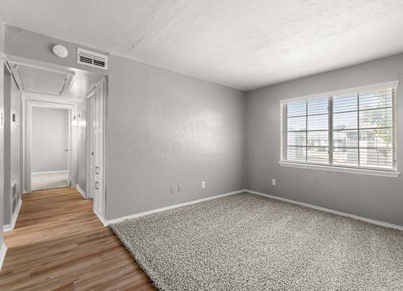 A room with a carpeted floor and a window with blinds.at The Sidney, Sherman, TX 75090