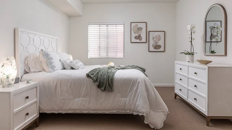 Model apartment bedroom with comfortable bedding and an orchid